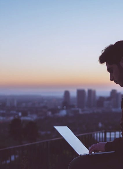 A person at a laptop above a skyline.