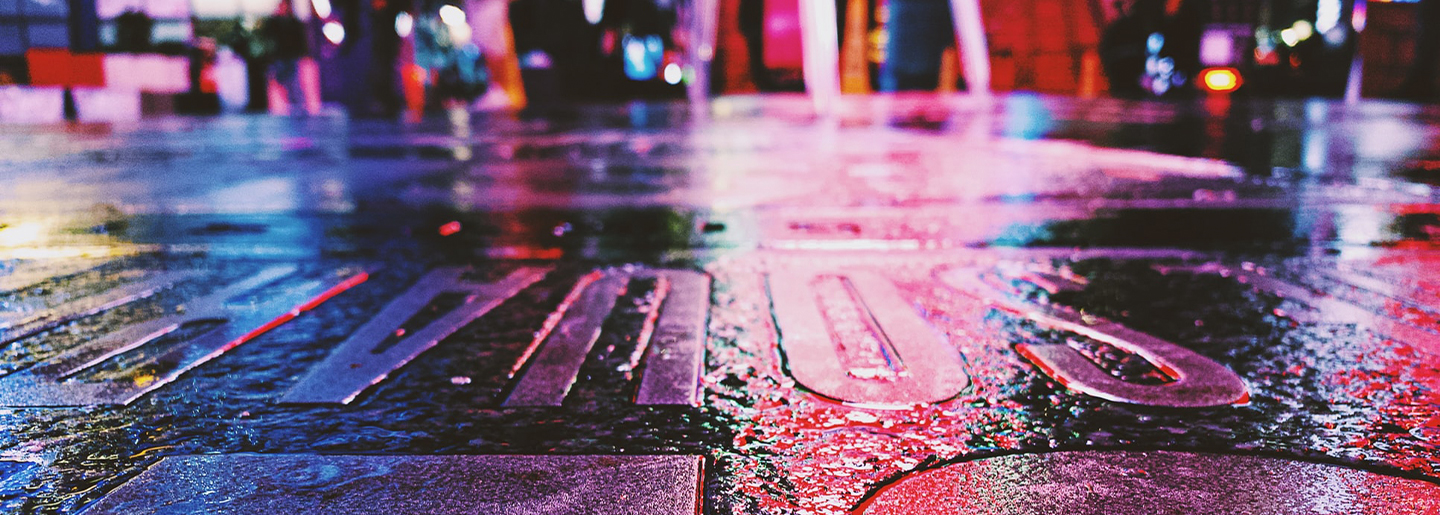 City lights shining against a wet pavement road.