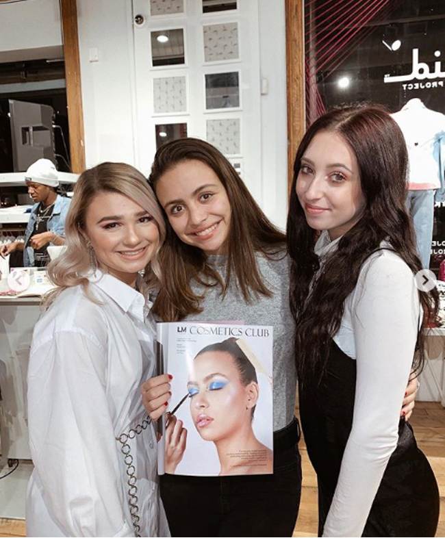 Three women holding up a copy of Cosmetics Club magazine