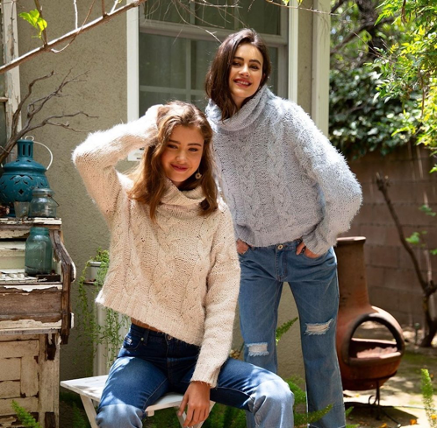 Two women wearing cable knit sweaters