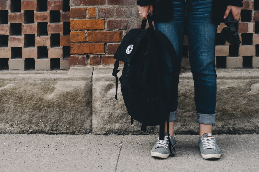 Student holding a Backpack by their feet