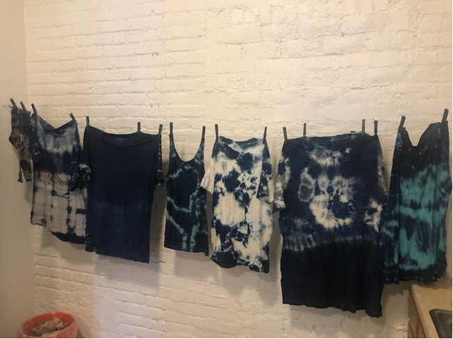 Tie-Dyed clothes hanging next to a white brick wall