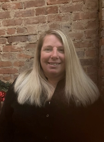 LIM faculty member Beth Hochberg smiles while standing in front of a brick wall