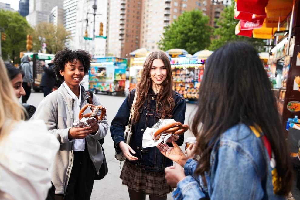 students in NYC with big street vendor pretzels