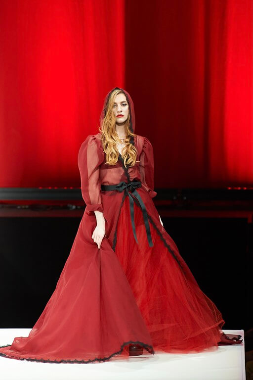 model on the runway in red dress with a hood