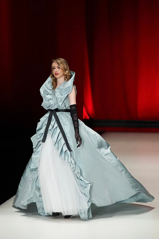 model on the runway in pale blue dress with black gloves