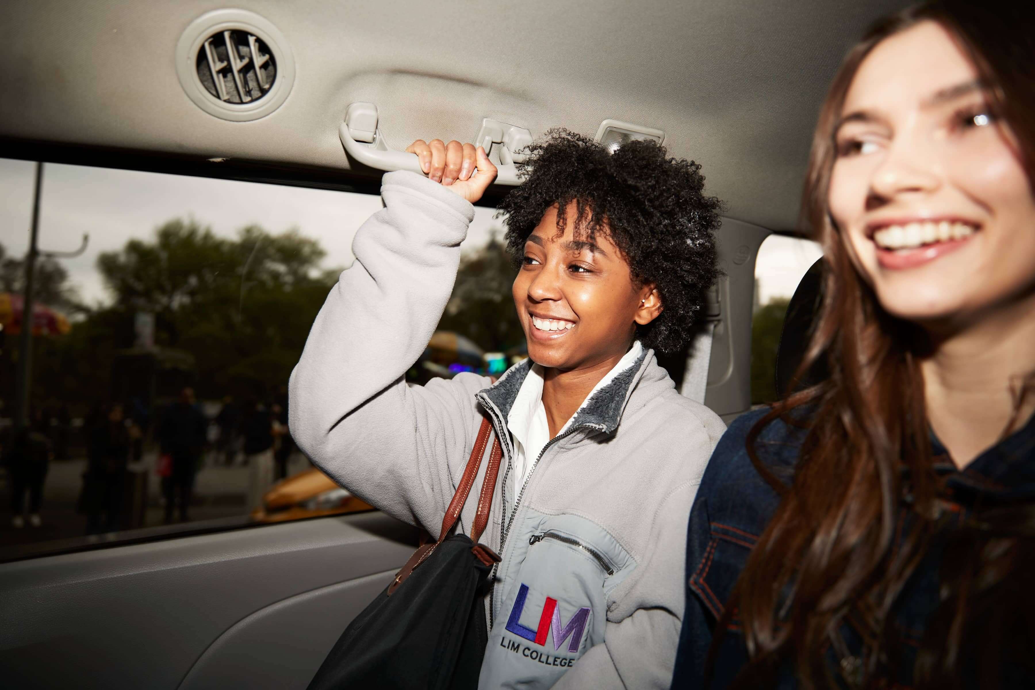 Two LIM students share a taxi in the busy streets of New York City. One student wears an LIM jacket