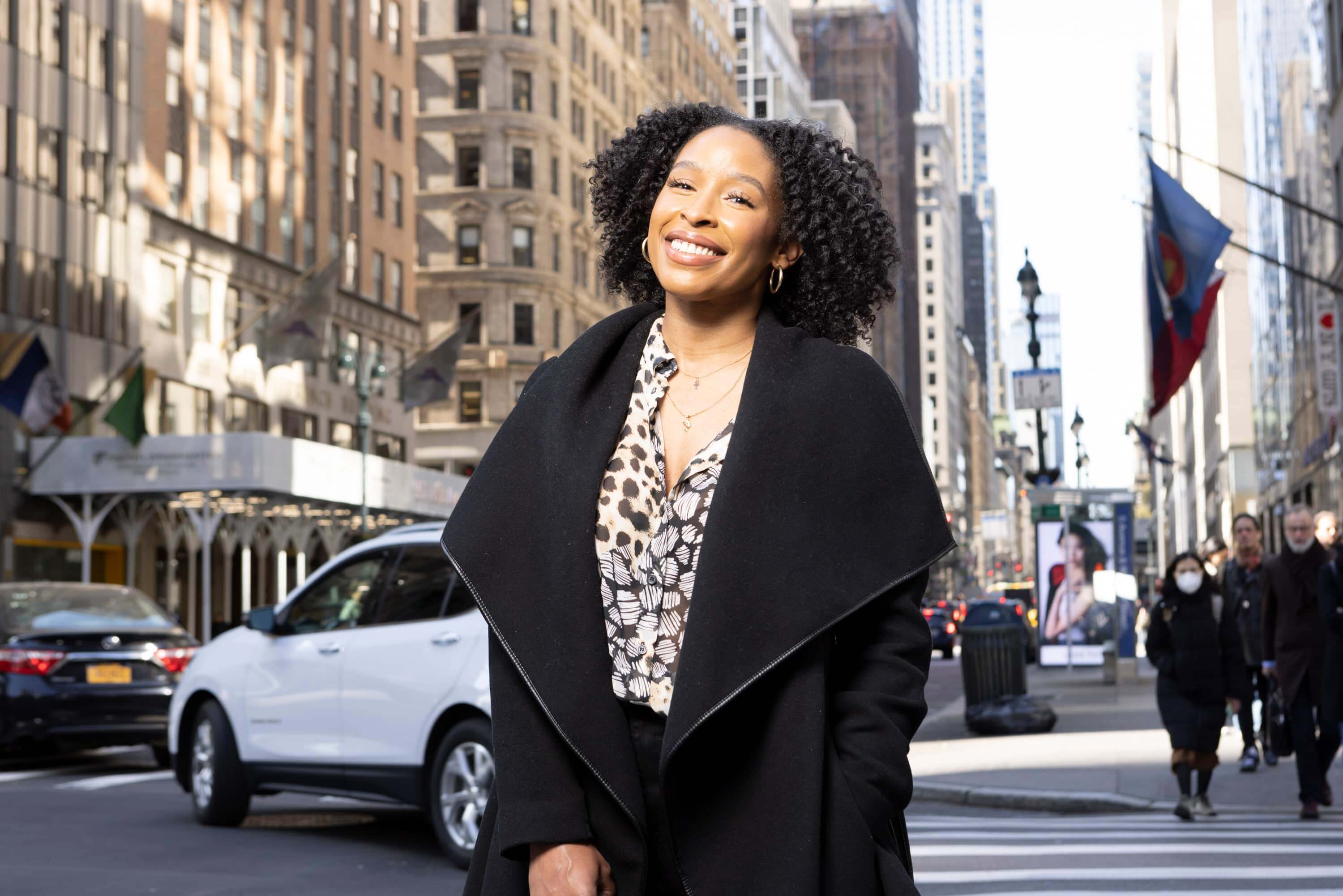 LIM alum Delisha Fields wears a black winter coat and smiles as she stands near the Met Life building in NYC