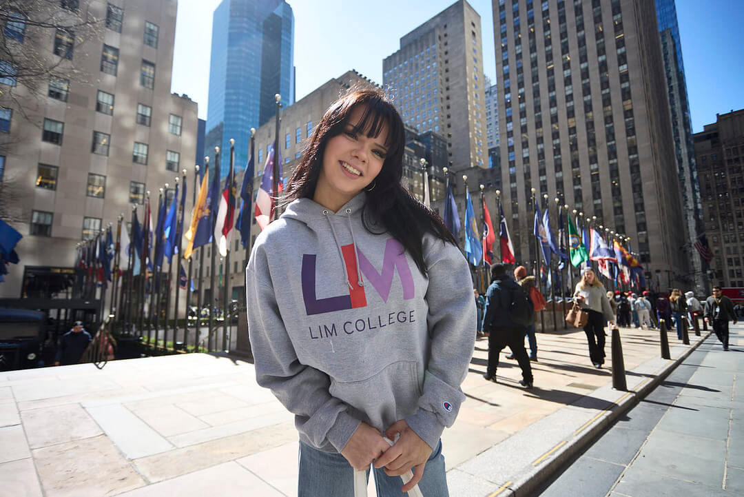 dark-haired young woman in LIM College hoodie, standing outdoors in Rockefeller Plaza