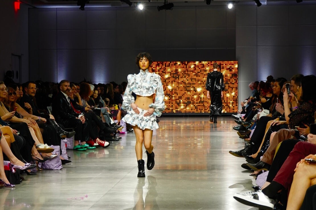 2025 Fashion Show, models on runway, landscape orientation, audience seated along sides