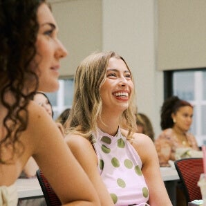 young woman, smiling, long blonde hair, LIM classroom, dotted sleeveless dress
