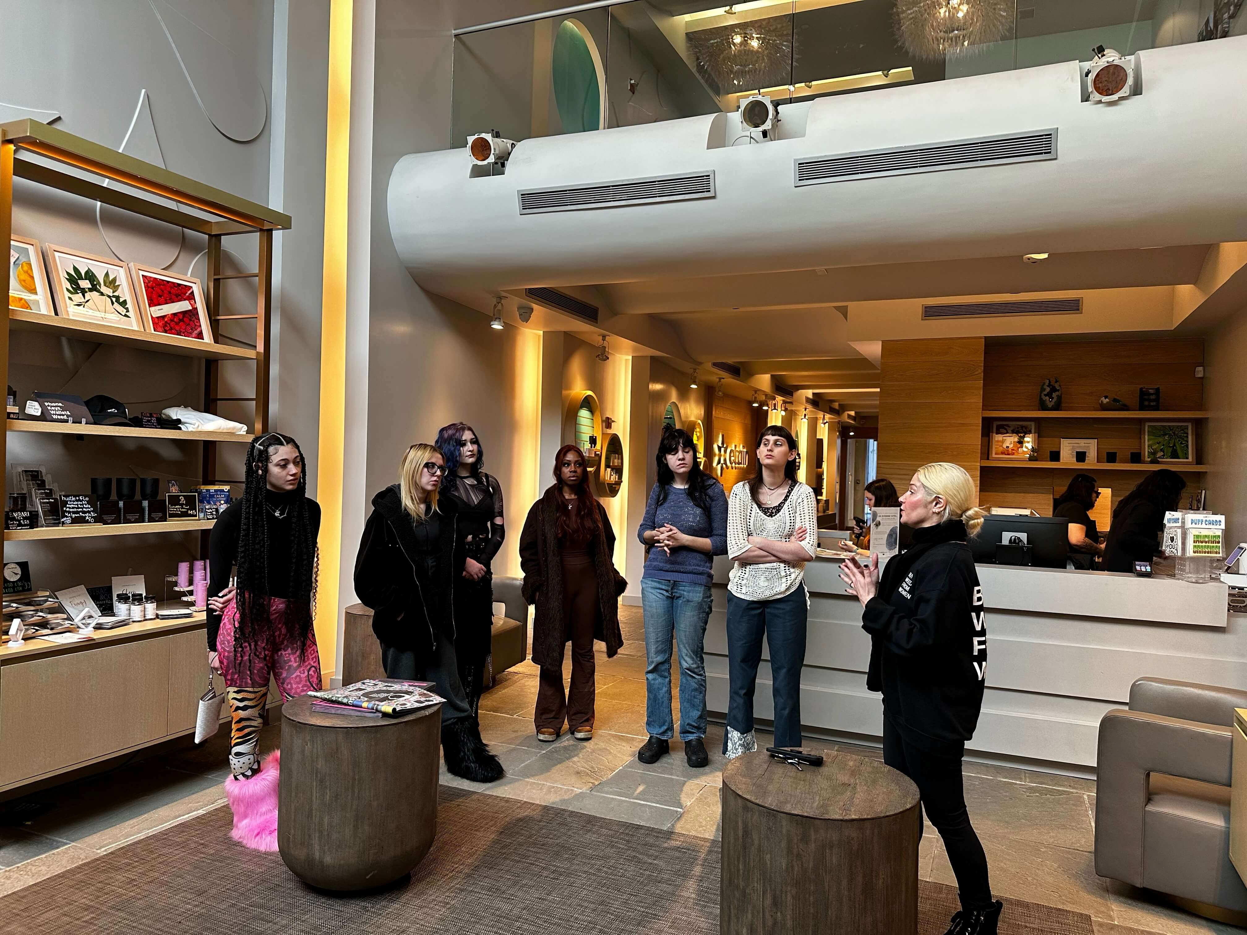 A group of a students gather around and listen to a speaker