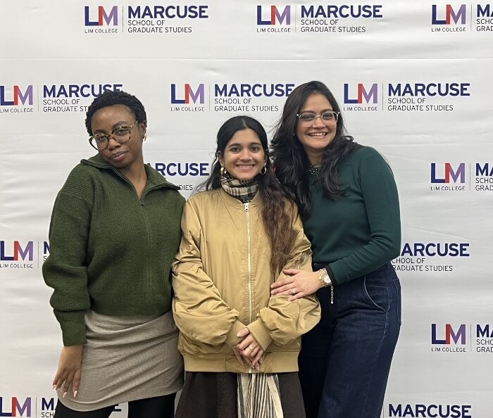 three graduate students in front of Marcuse School of Graduate Studies step and repeat