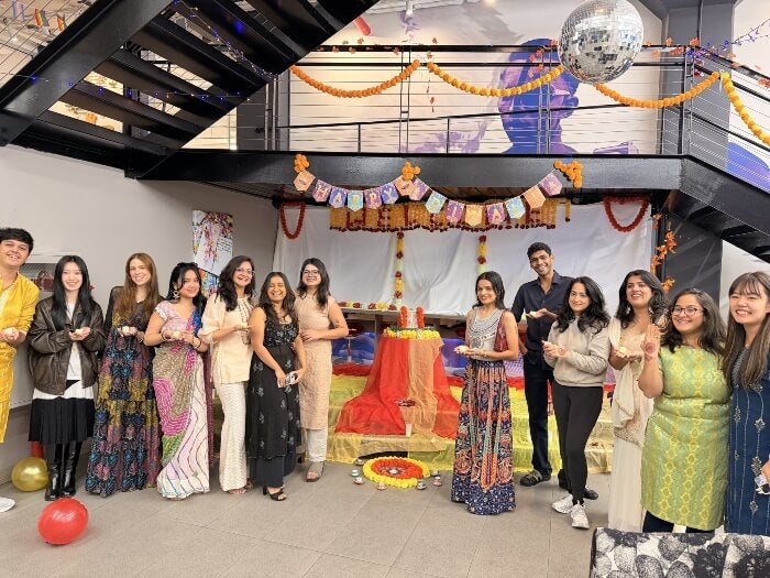 LIM College Diwali celebration in Maxwell Hall Center, many celebrating students stand together, staircase in background