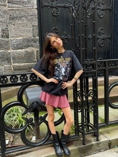 Maddie stands in front of NYC metal fence, boots