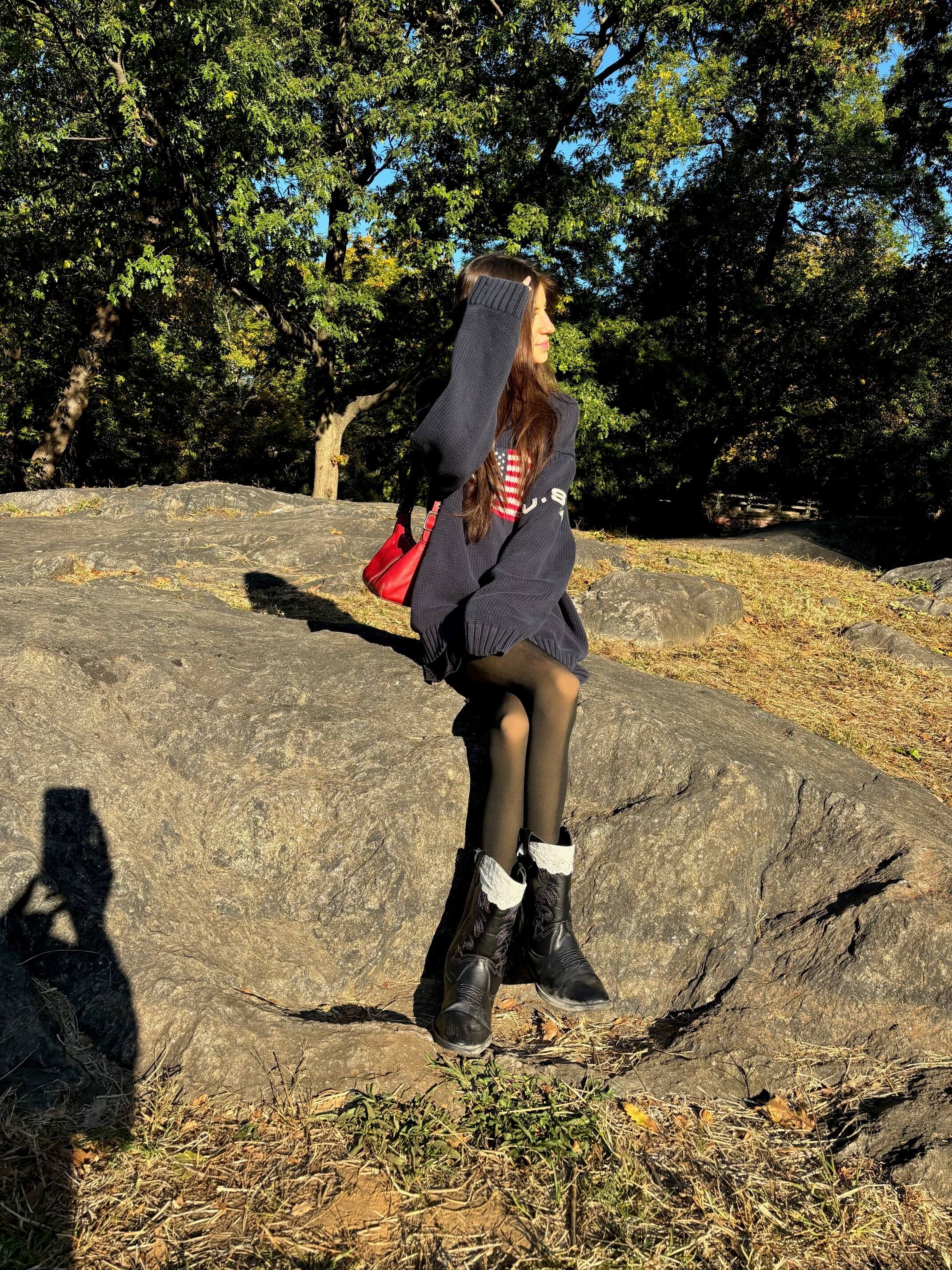 Maddie sits on a rock in the park.