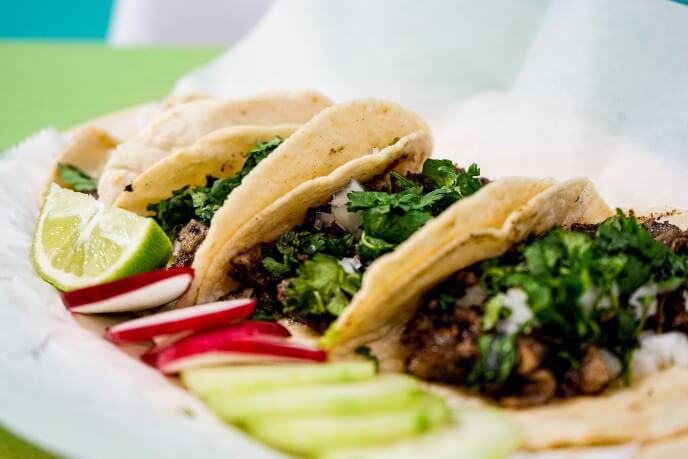 Three tacos on a parchment-lined dish.