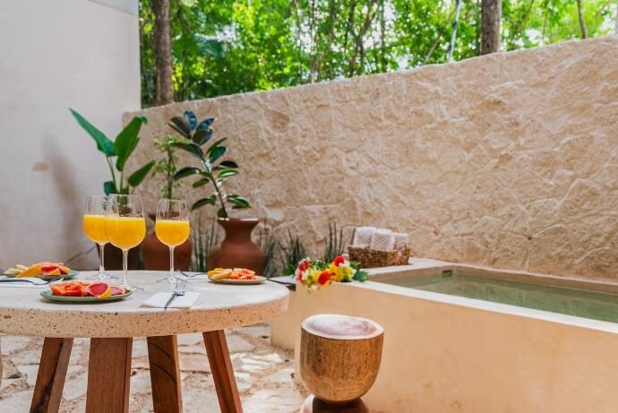 Tulum property, adobe walls and batch, outdoor patio, drinks and food on a round table