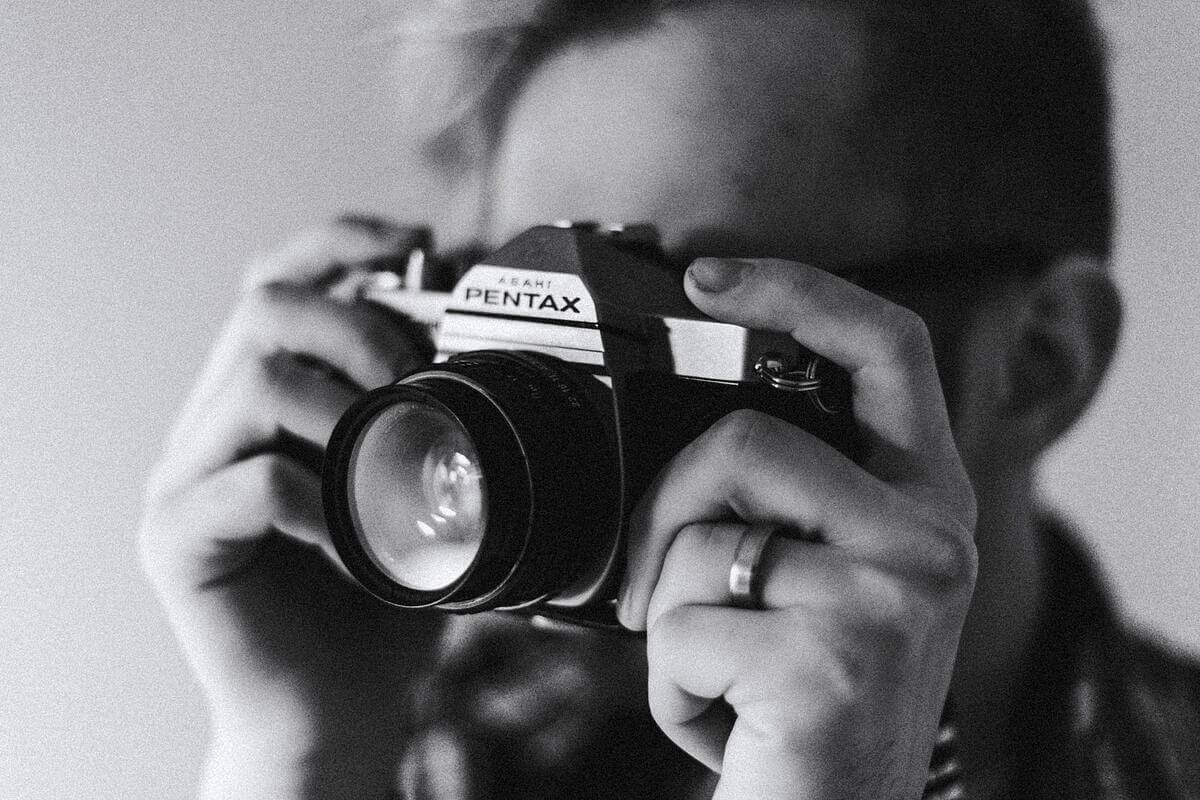 A man looks through a Pentax camera