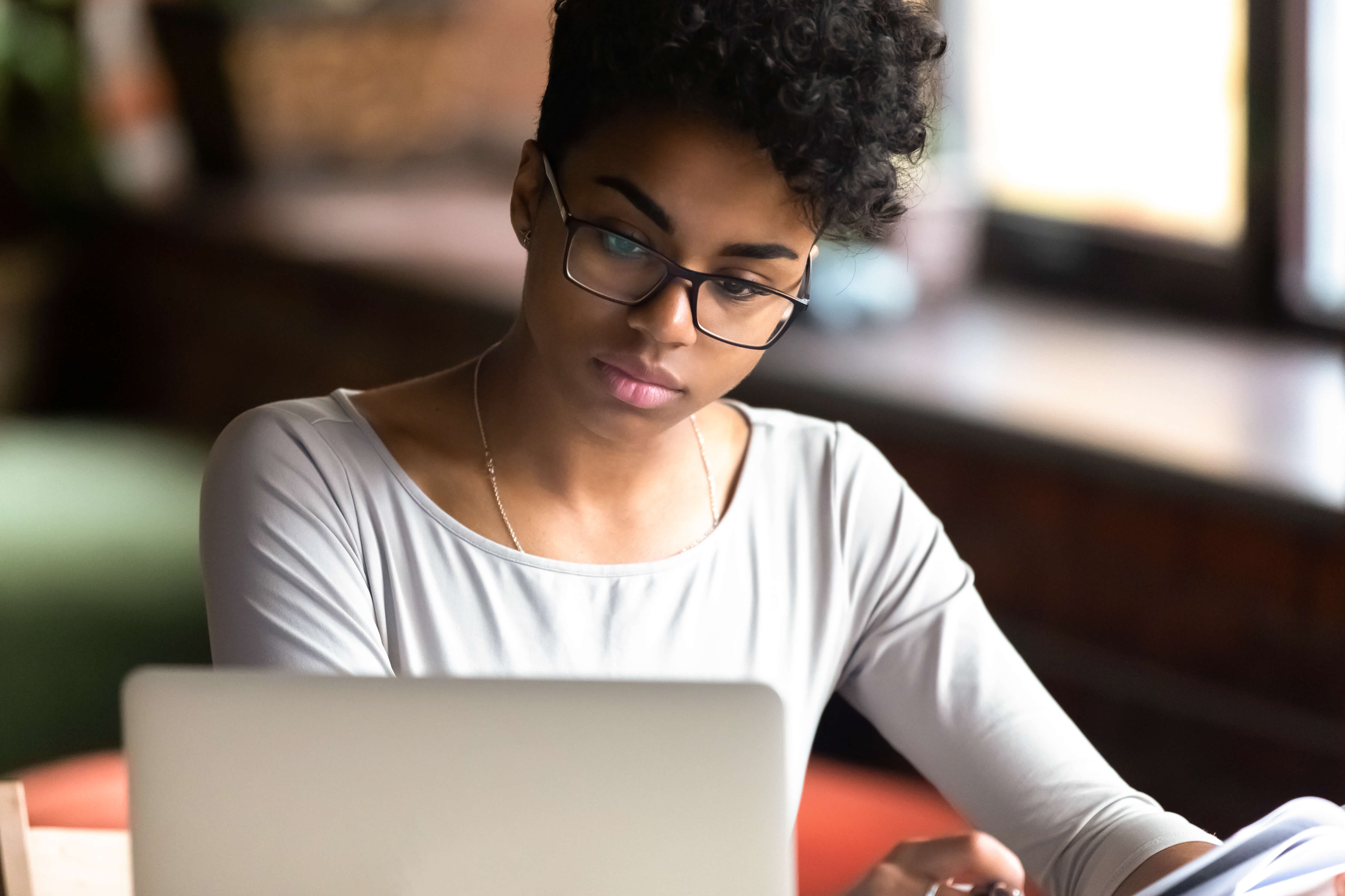 A female sits at a desk looking at a laptop