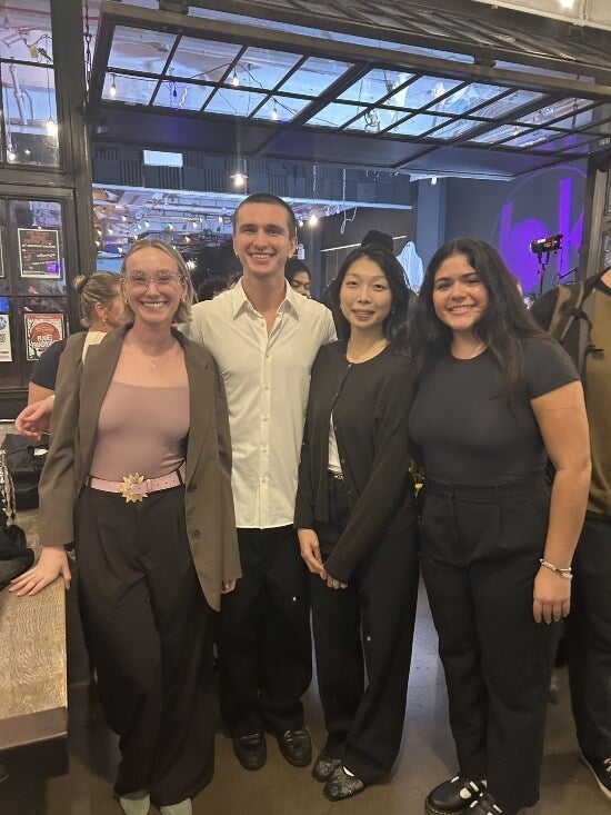 Four LIM grad students stand posing near a showroom in Industry City, Brooklyn
