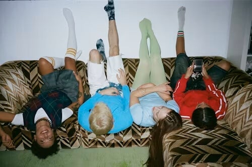 young people lying upside down on a pattern-upholstery couch