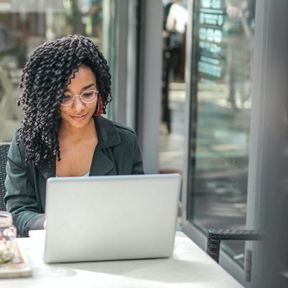 A student working at her computer from a coffee shop.