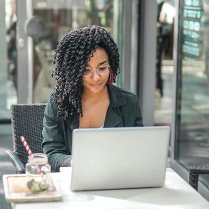 A student working at her computer from a coffee shop.