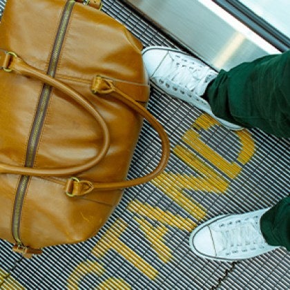 A suitcase at someone's feet at the airport.