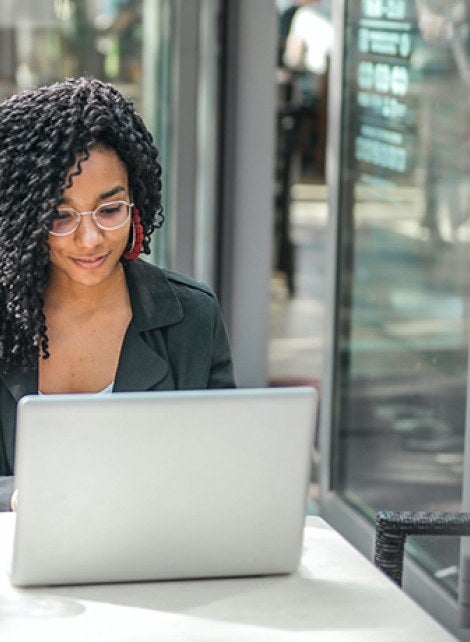 A student working at her computer from a coffee shop.