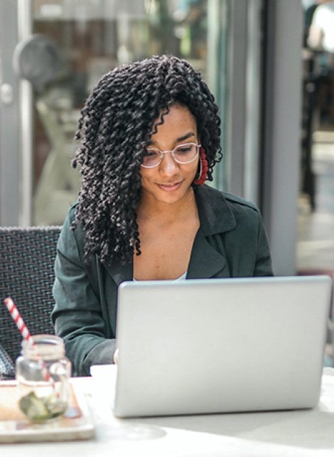 A student working at her computer from a coffee shop.