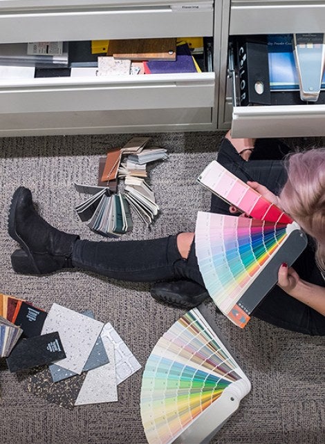 A person on an office floor going through a spread of color pallets.