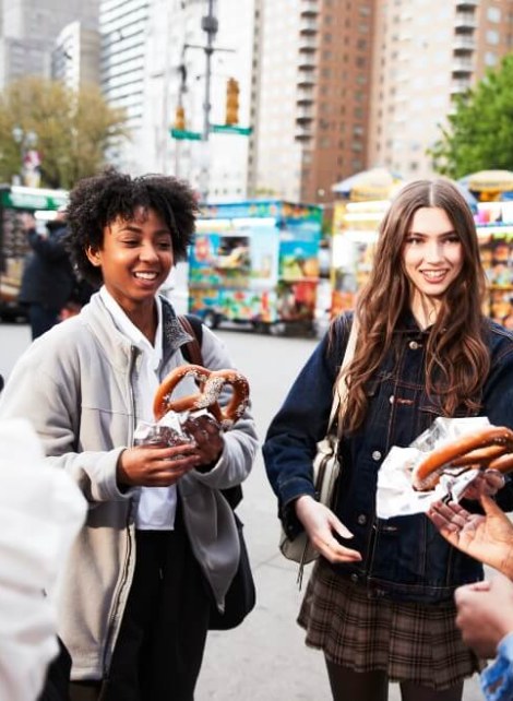 students in NYC with big street vendor pretzels