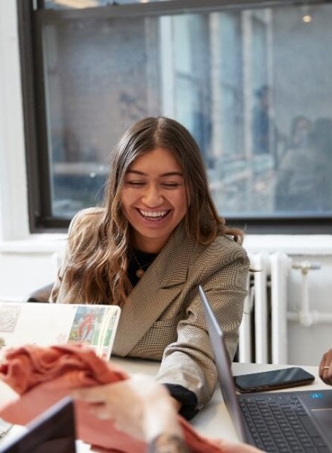 female student in tan jacket in open concept classroom on campus