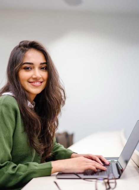 woman brown hair green sweater on laptop in classroom