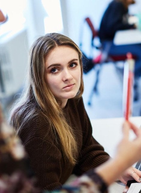 Blonde student in classroom, red sweater