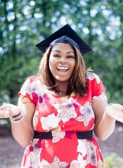 woman in graduation cap, smiling and shrugging
