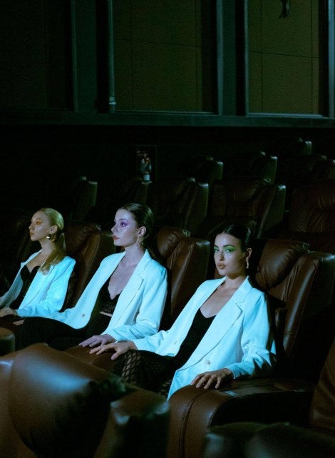 dark viewing theater, female audience members in white blazers