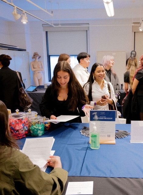 students at career fair table, handing out resume, speaking with employers, LIM classroom