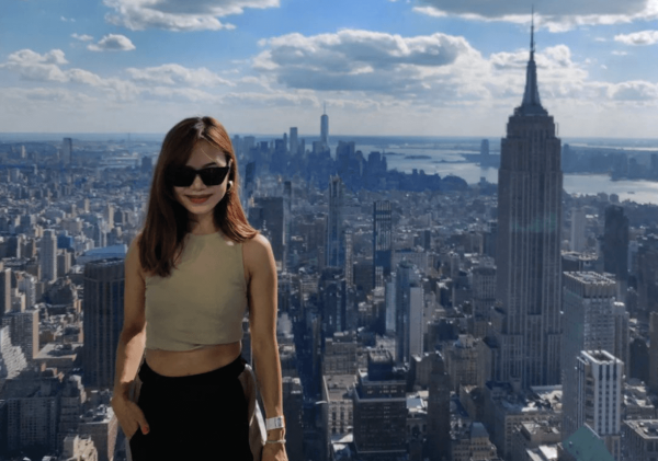 Apurva on skyscraper rooftop with New York City in background