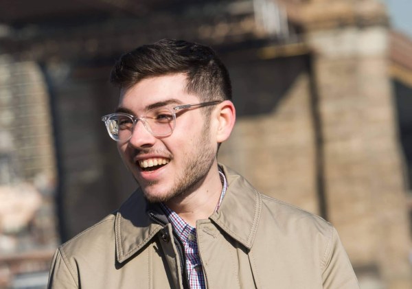 LIM alum Thomas J. Giangrande smiles as he speaks with someone while standing near the Brooklyn Bridge
