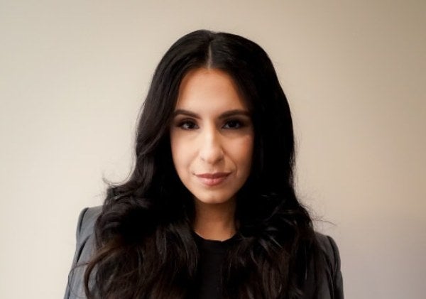 woman, professional photo, dressed in black with jacket folded over shoulders, arms folded