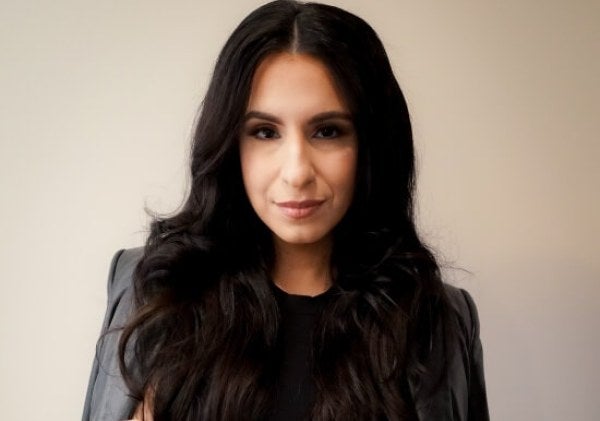 woman, professional photo, dressed in black with jacket folded over shoulders, arms folded