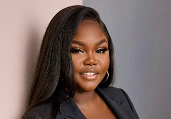 woman with long dark hair, earrings, charcoal business suit, medium shot