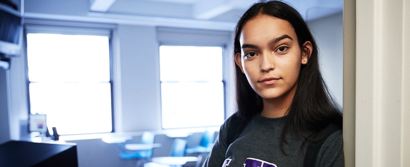 student in classroom doorway wearing LIM shirt