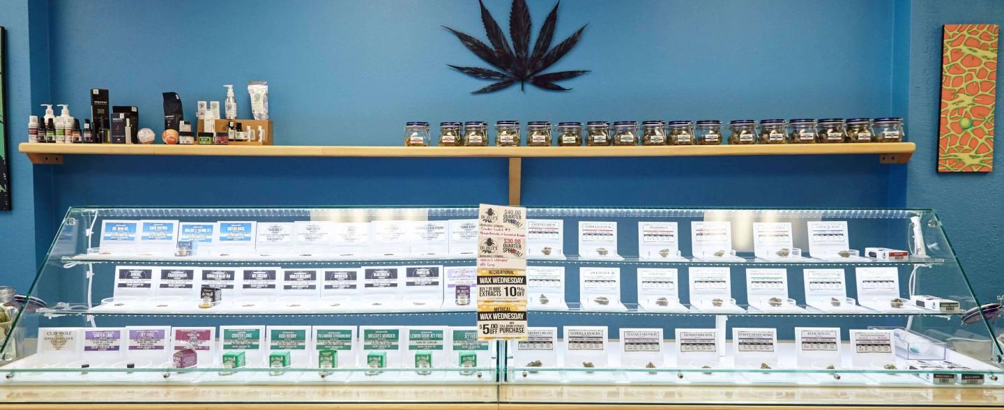 A cannabis dispensary displays cannabis products behind a glass case and on a shelf