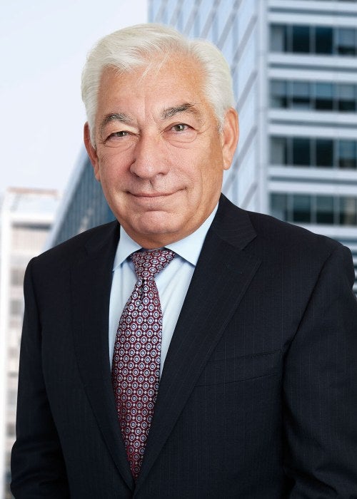 man standing in front of a building in a dark suit and tie