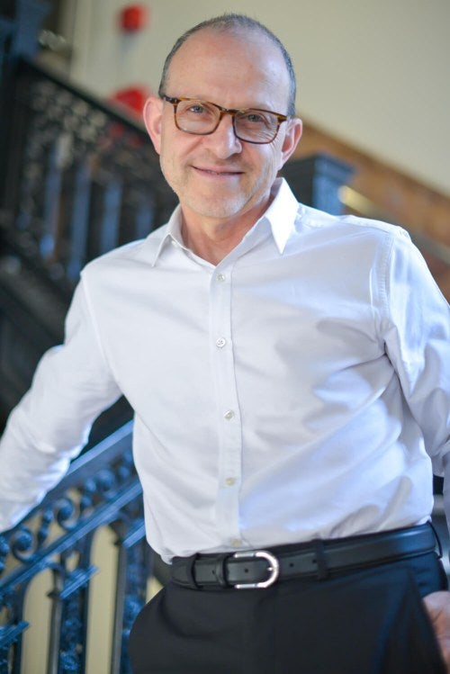 man with glasses posing in front of stairs