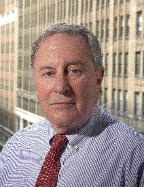 photo of a stoic man with buildings in the background