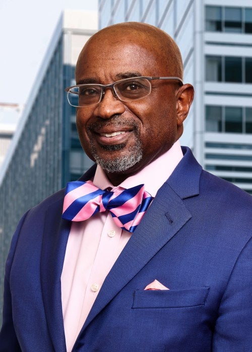 man in blue suit with pink and blue bow tie and glasses